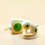 Close-up of toy front-load washing machine showing green circular door and control dials