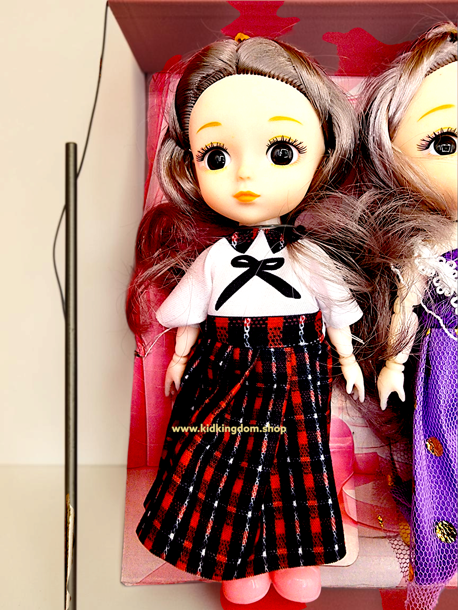 Close-up view of four mini dolls wearing purple gown, floral, and plaid fashion dresses