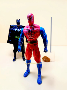 Close-up of superhero action figure chest emblem showing the light-up button feature